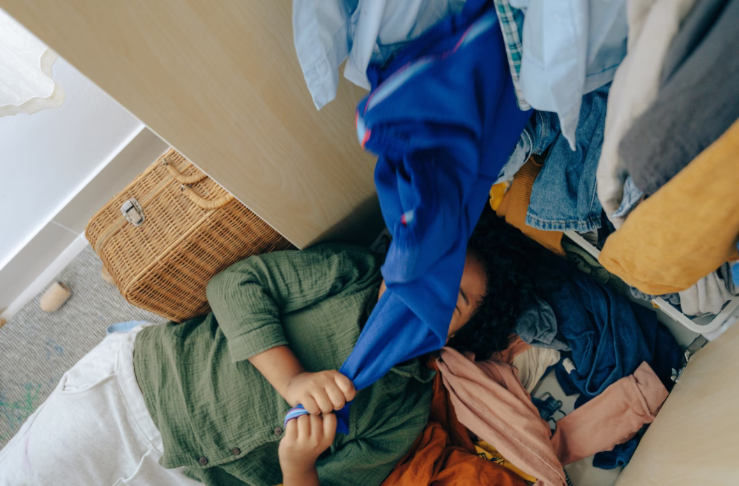 Girl lying on clothes in messy bedroom