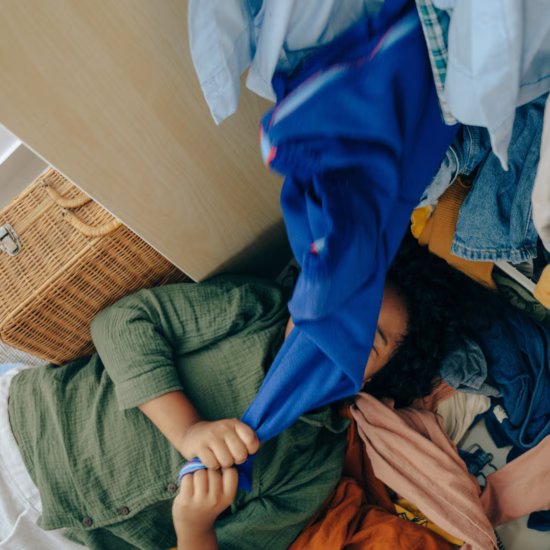 Girl lying on clothes in messy bedroom
