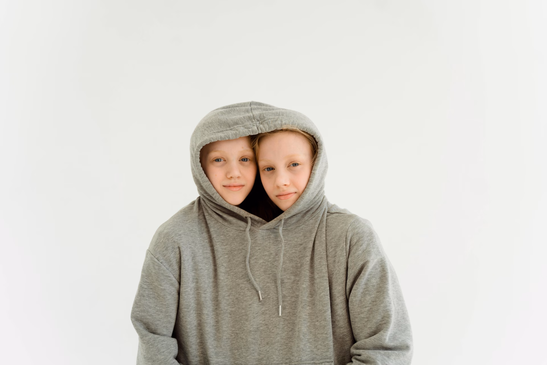 Autistic twin girls share an oversized grey hoodie.