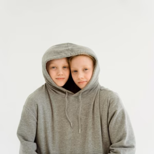 Autistic twin girls share an oversized grey hoodie.